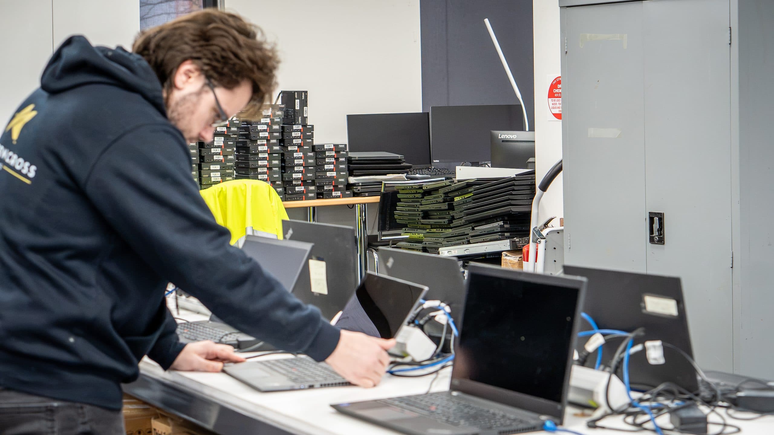 Rows of new laptops being configured on a deployment bench
