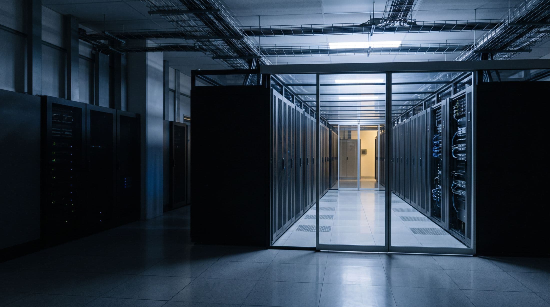 A dimly lit server aisle with racks of equipment under cool light