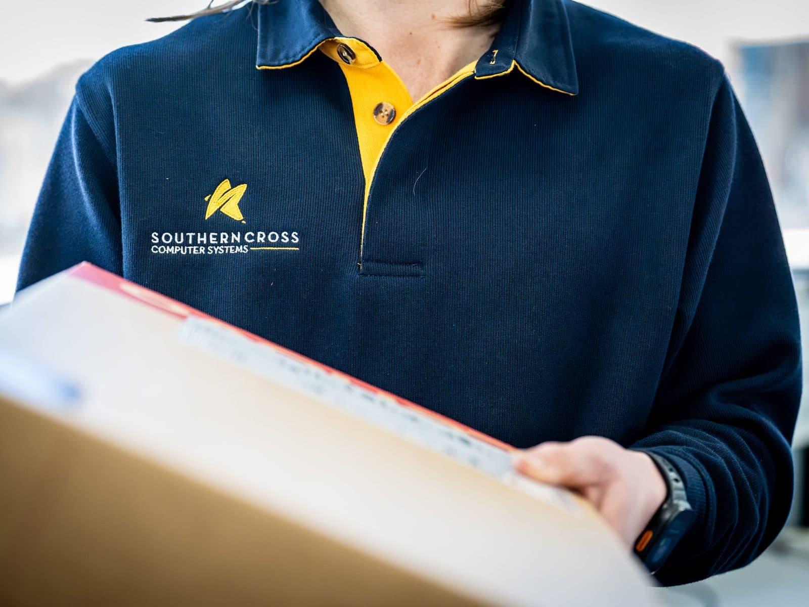 An SCCS team member in uniform carrying a boxed laptop for deployment