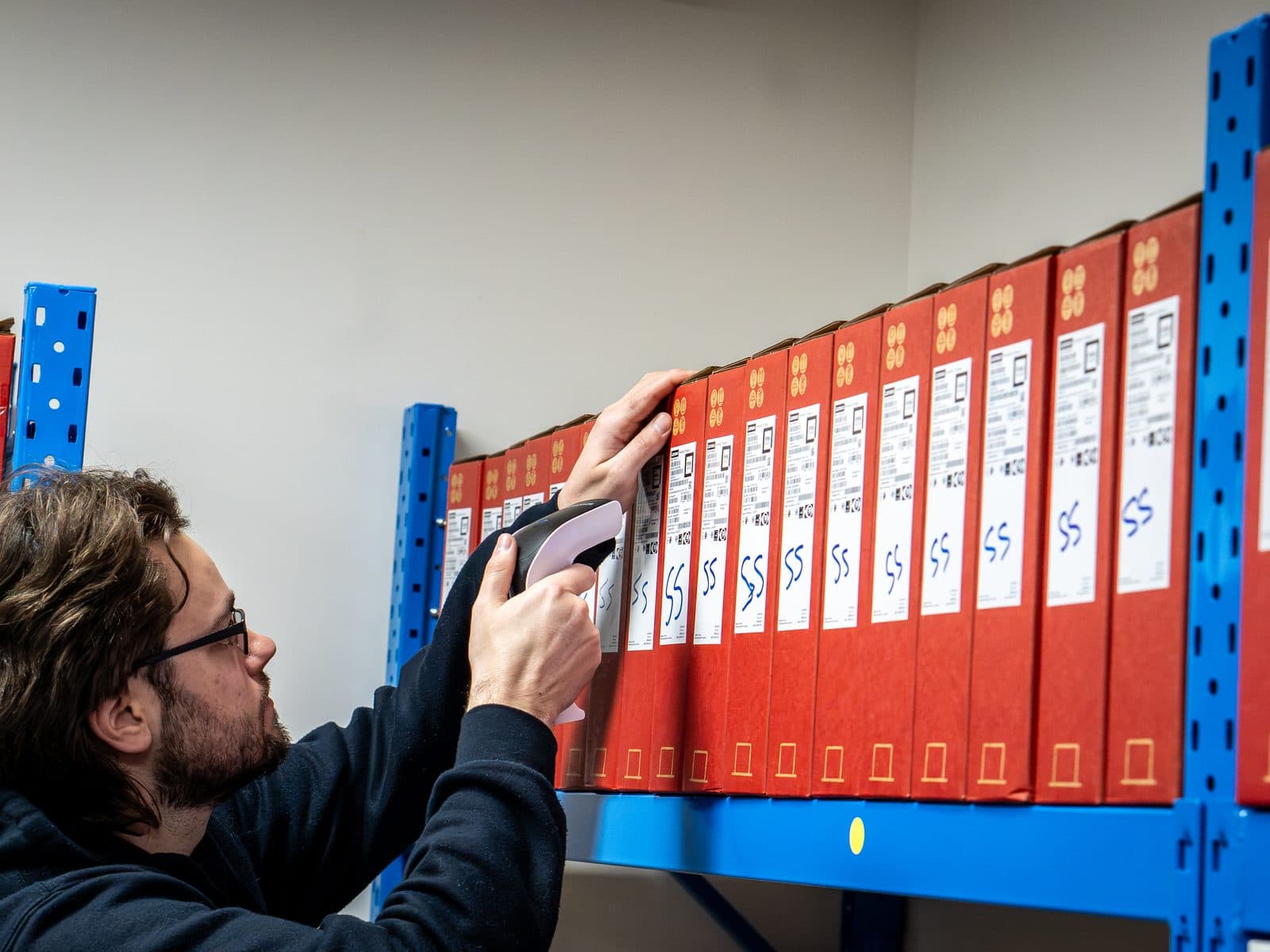 An SCCS technician scanning boxed devices on the warehouse racking